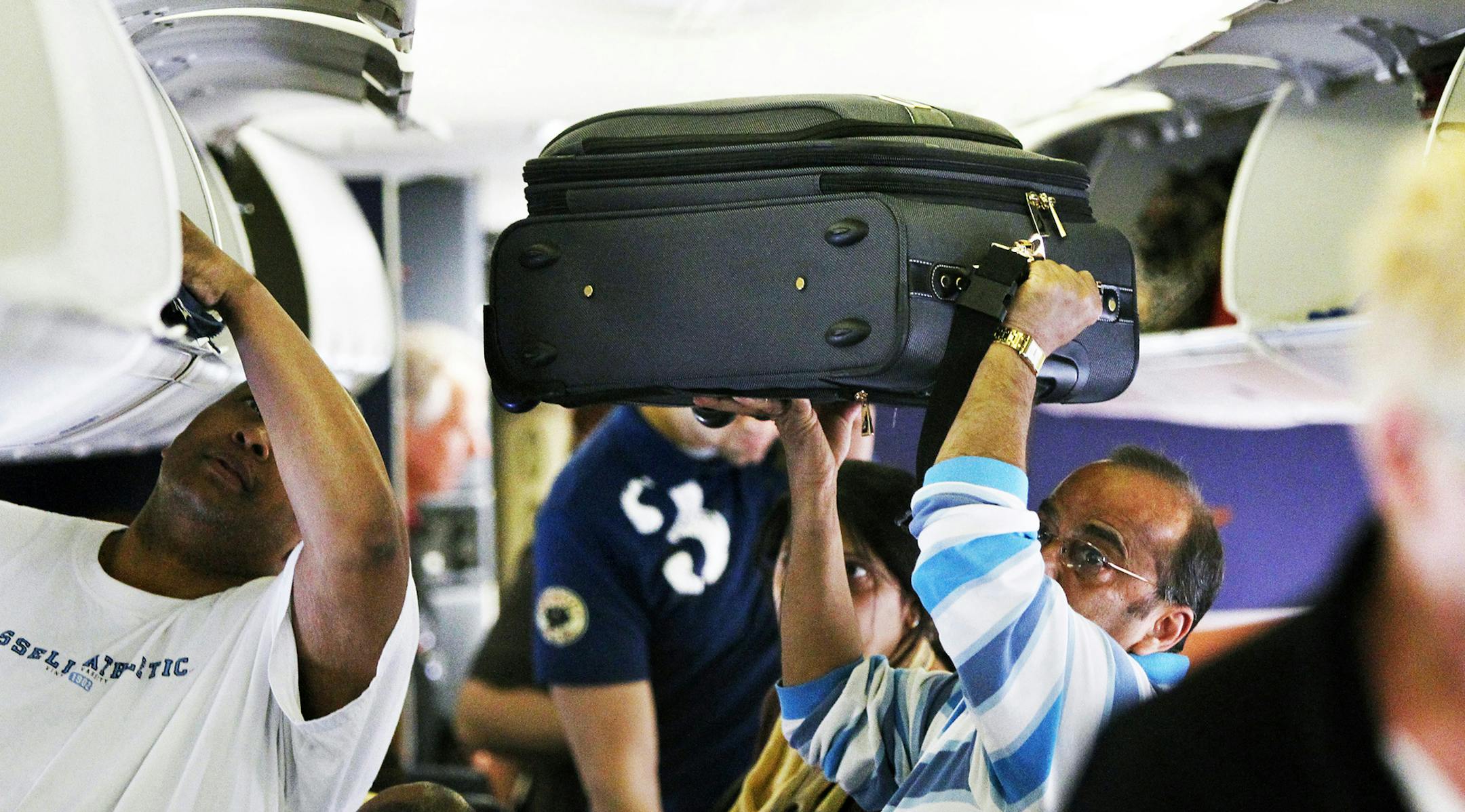 A Southwest Airline passenger lifts his luggage into the air while looking for a storage spot in the overhead compartments before a flight from Midway Airport in Chicago to Cleveland, Ohio, April 2, 2010. (Chris Sweda/Chicago Tribune/MCT) ORG XMIT: MIN2017032814400631