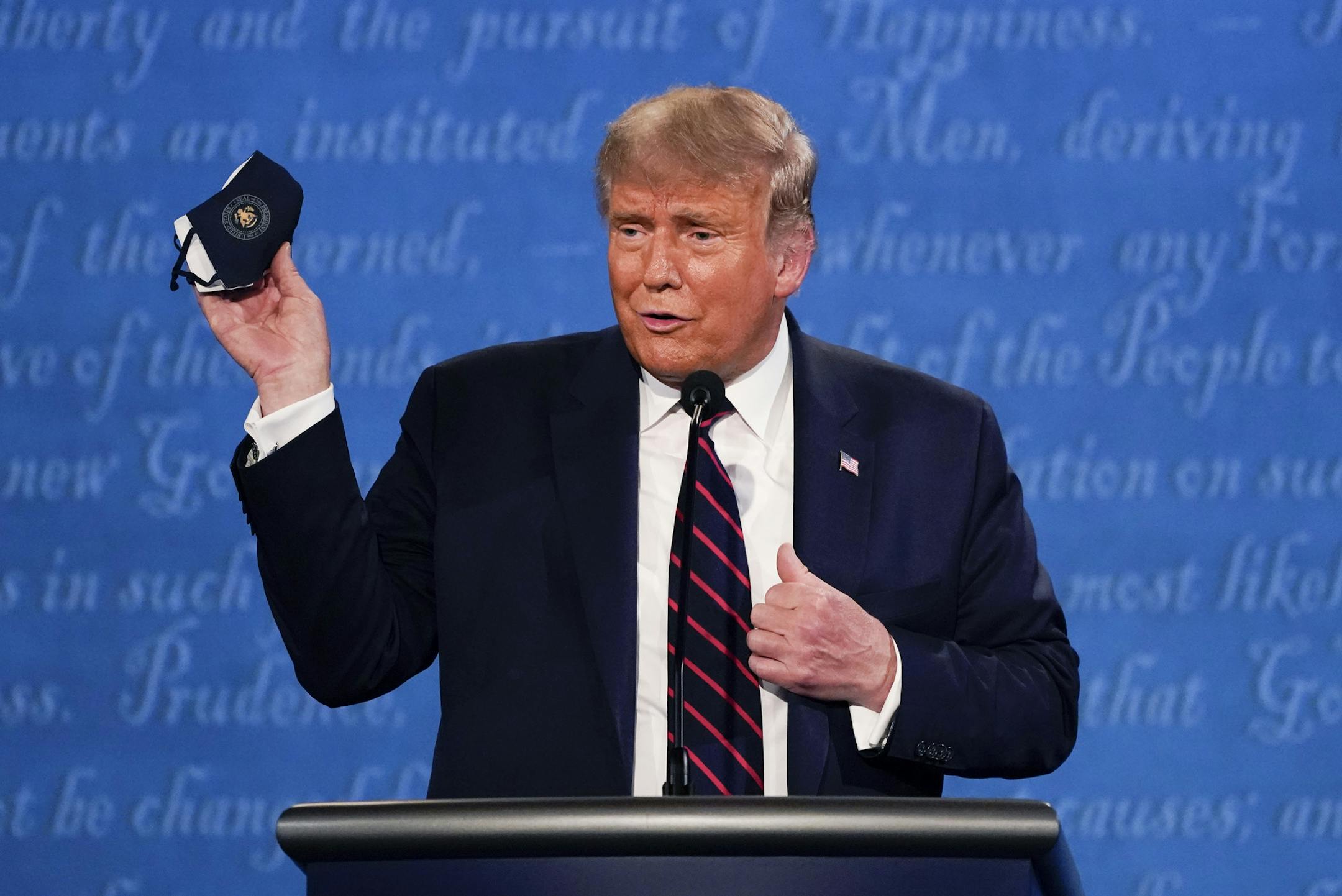 FILE - In this Sept. 29, 2020, file photo, President Donald Trump holds up his face mask during the first presidential debate at Case Western University and Cleveland Clinic, in Cleveland, Ohio. Before President Donald Trump contracted the coronavirus, British Prime Minister Boris Johnson and Brazilian President Jair Bolsonaro both fell ill with COVID-19. If their experiences are any guide, there's no guarantee Trump will be changed by COVID-19. (AP Photo/Julio Cortez, File)