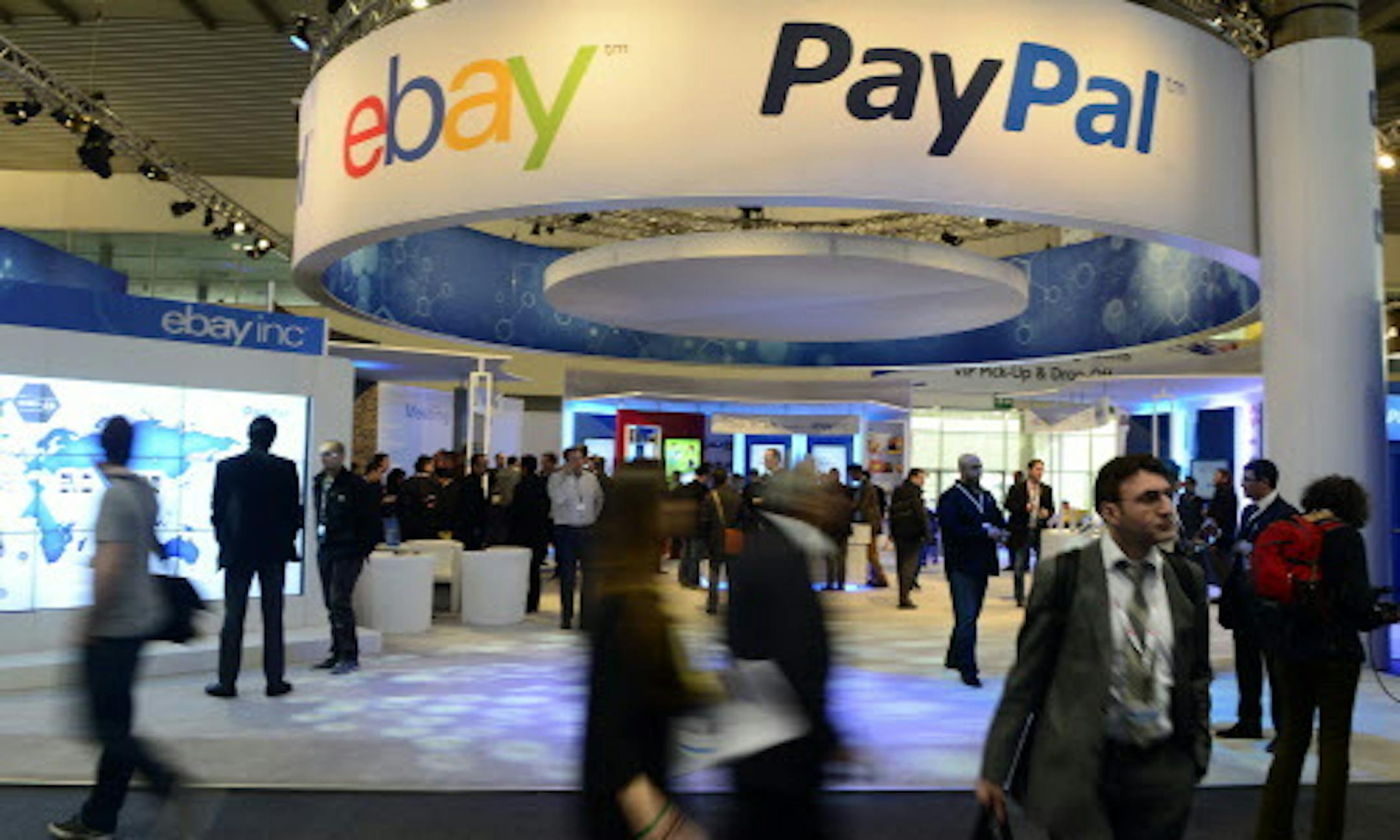 FILE - In this Wednesday, Feb. 27, 2013, file photo, attendees walk in front of an EBay and PayPal display area at the Mobile World Congress, the world's largest mobile phone trade show, in Barcelona, Spain. PayPal is splitting from EBay Inc. and will become a separate and publicly traded company during the second half of 2015. (AP Photo/Manu Fernandez, File)