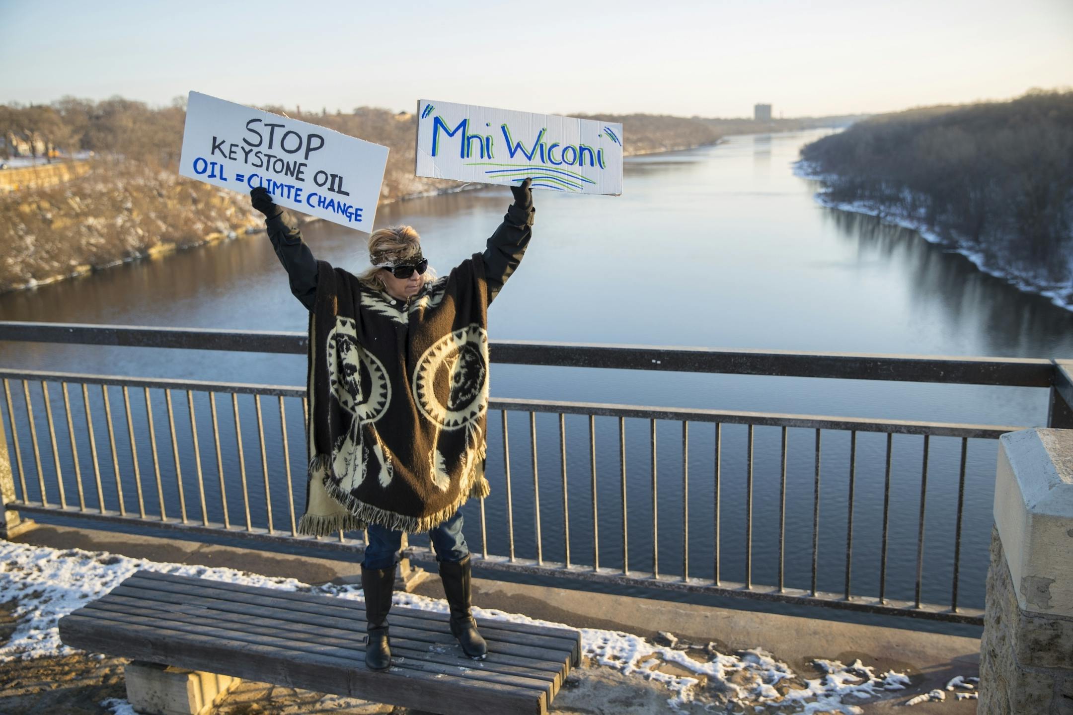 Tereza Holguin (CQ), of St. Paul, held up signs as she stood on the outskirts of about 500 people gathered on the Marshall Avenue Bridge (Lake Street) to protest the Dakota Access Pipeline on the border of St. Paul and Minneapolis, Minn., on Friday, January 27, 2016.