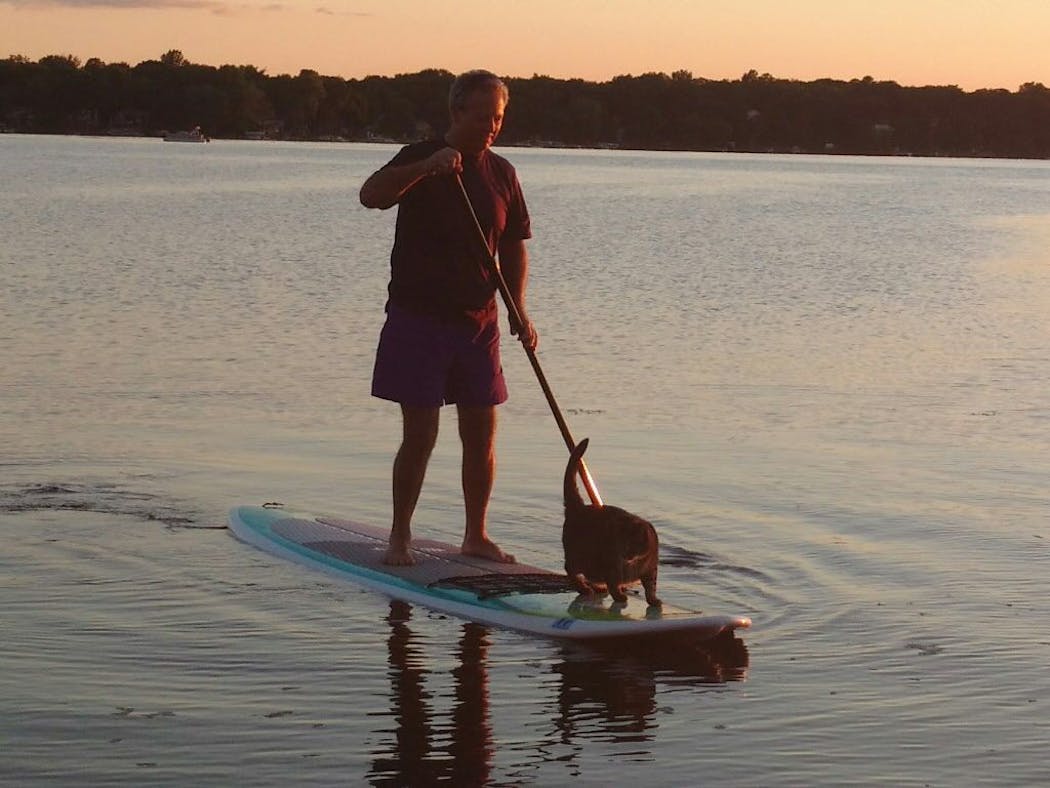 Craig Reed and Max the cat like to go paddleboarding on Forest Lake.