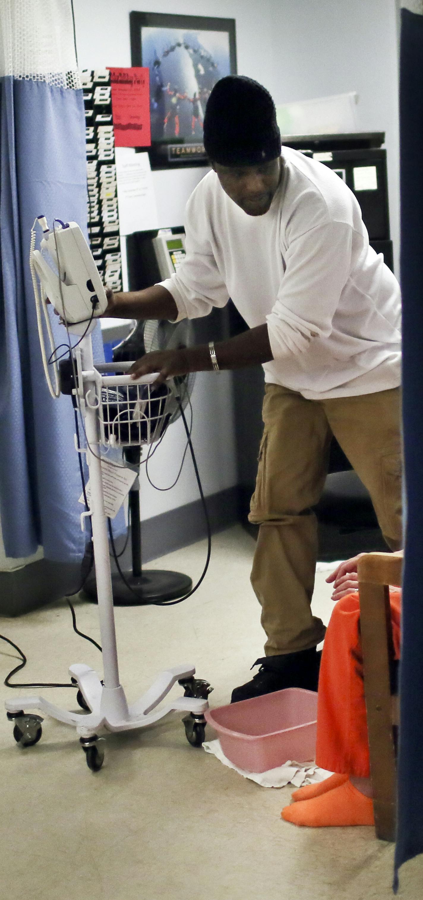 Hennepin County Detox Center health care assistant Sidney McVay prepared to take the vital signs of a distraught patient.