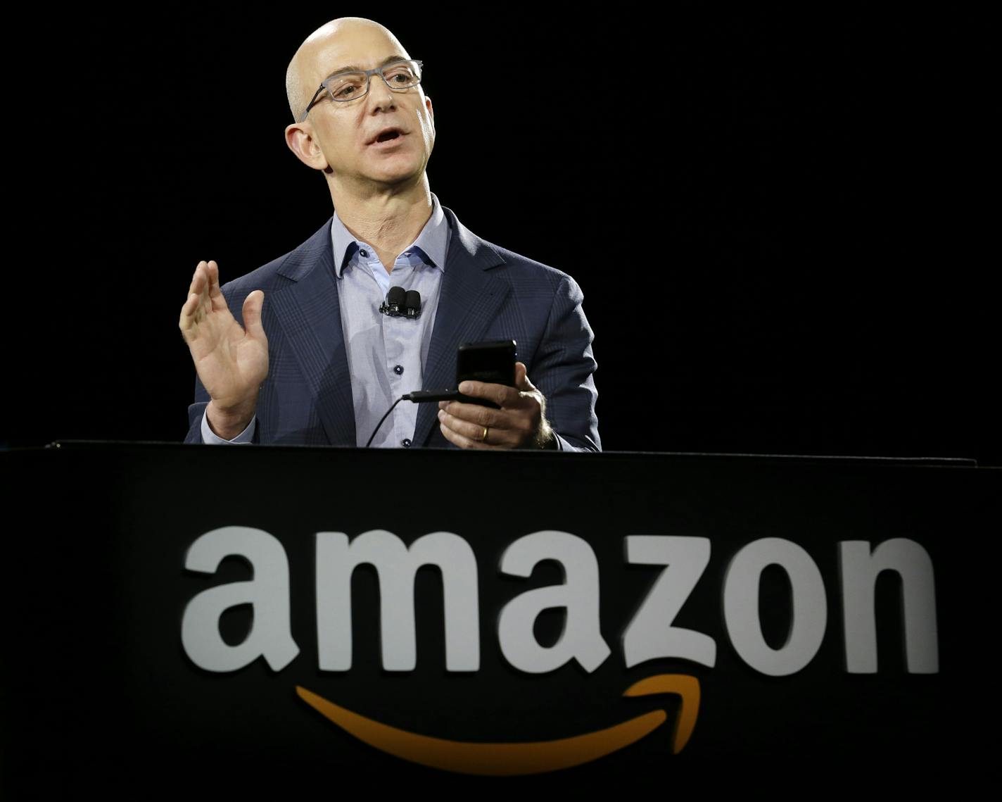 Amazon CEO Jeff Bezos demonstrates the new Amazon Fire Phone, Wednesday, June 18, 2014, in Seattle. (AP Photo/Ted S. Warren) ORG XMIT: WATW106