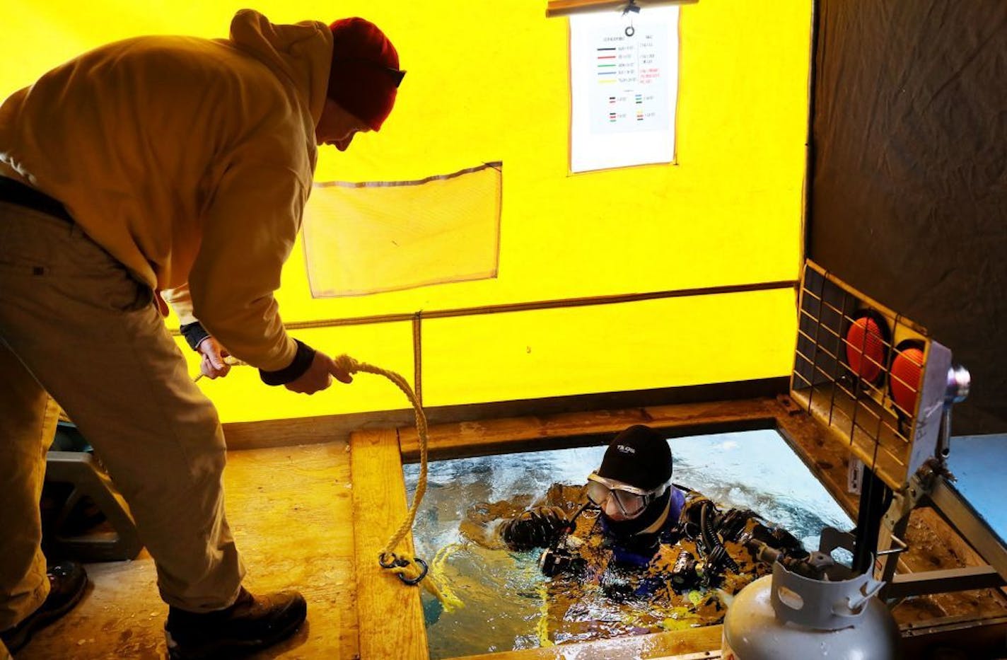 Members of the Great Lakes Shipwreck Preservation Society dove under the ice on Lake Minnetonka to take video of a shipwreck that they'll use to create a 3-D image of a boat wreck there Saturday, Feb. 16, 2019, near Carson Bay in Wayzata, MN. Here, GLSP diver Andrew Goodman surfaces after being the first diver into frigid Lake Minnetonka while being tethered to a safety line tended to by Jeff LeMoine.