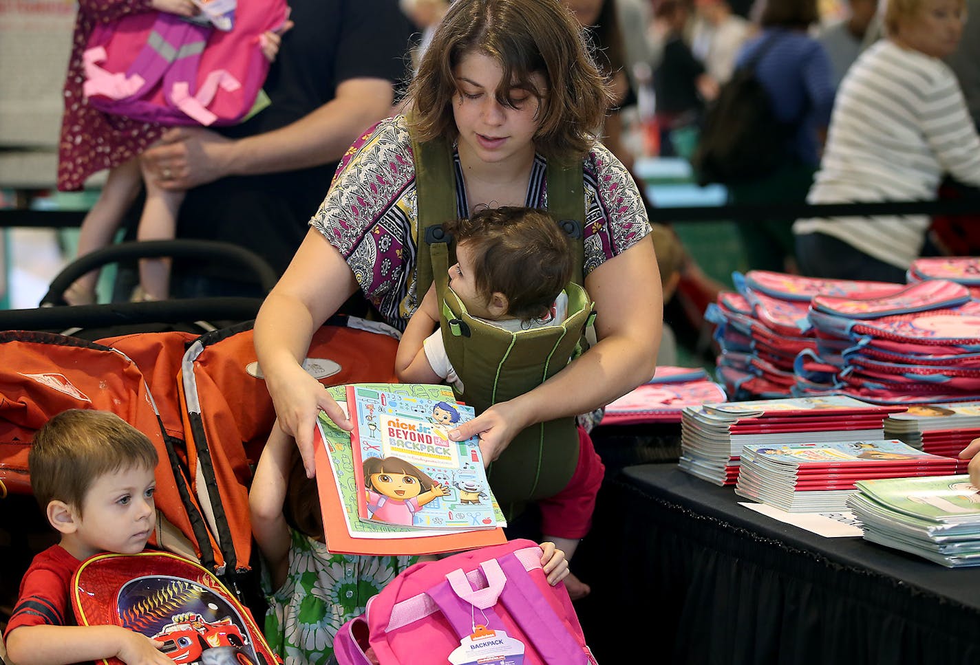 Tiffany Silva brought Koen, 2, left, Adie, 4, and baby Layna to help fill backpacks for local students at the Mall of America on Tuesday.