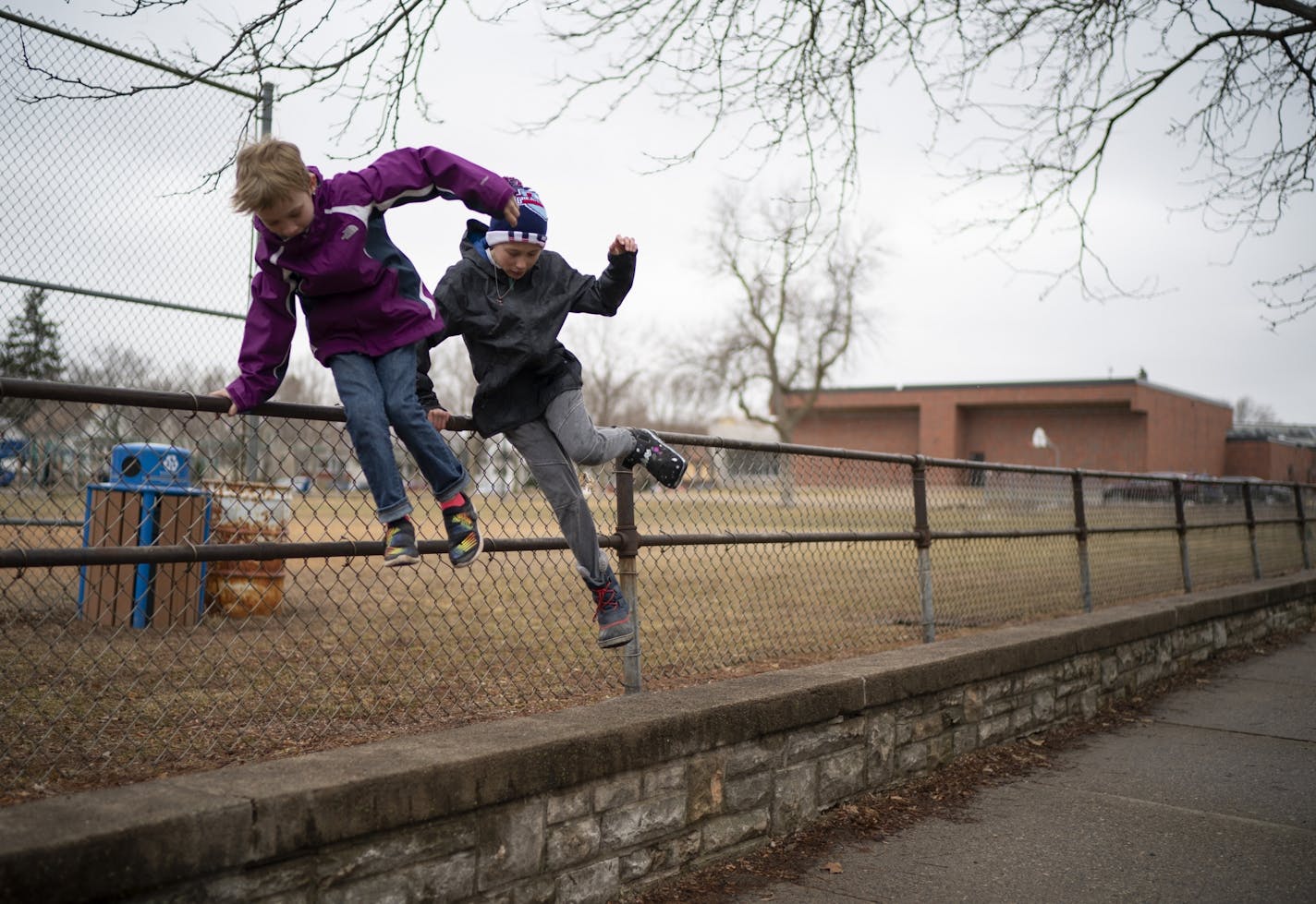 Lucy, left, and Frannie Howatt hopped over the fence of the playground at their neighborhood school, Galtier Elementary in St. Paul after visiting the playground.