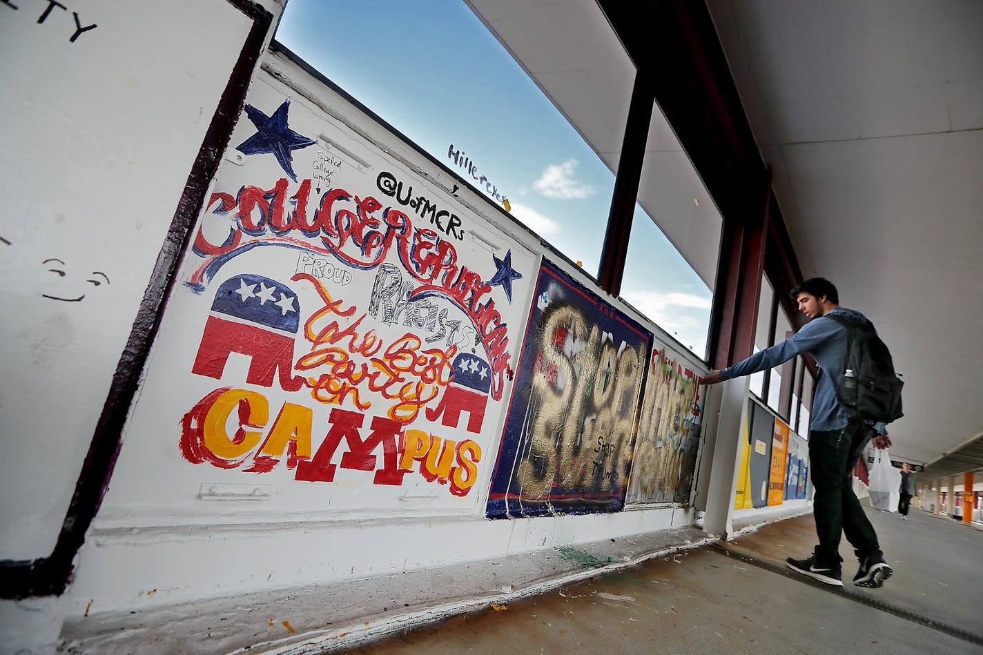 Dan Kreft, a senior psychology major at the University of Minnesota, showed a friend some graffiti that is rousing controversy over a &#x201c;build the wall&#x201d; message that university college Republicans painted on the Washington Avenue bridge, and others painted over, Tuesday, October 4, 2016 in Minneapolis.