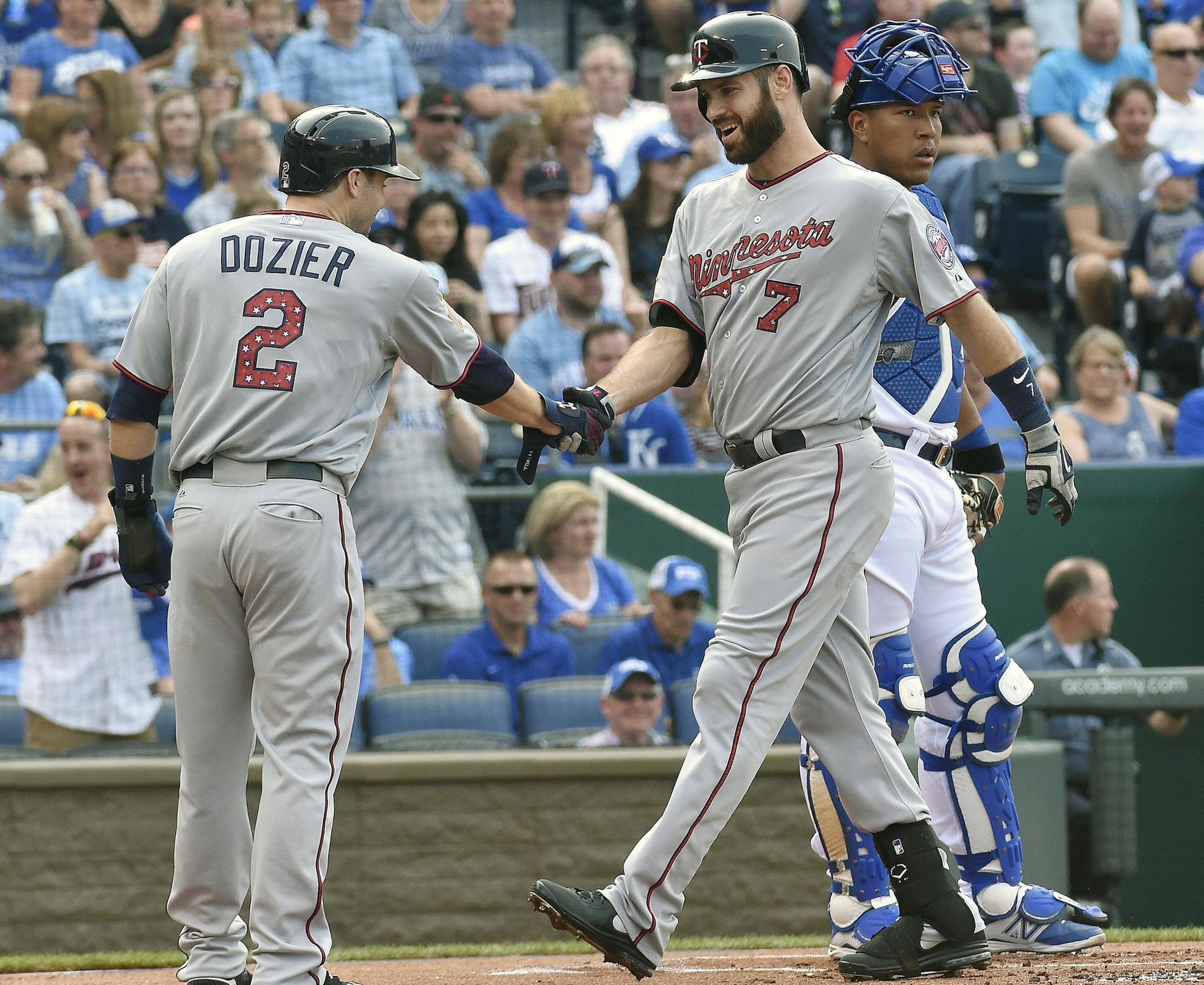 The Minnesota Twins' Brian Dozier (2) greets Joe Mauer in front of Kansas City Royals catcher Salvador Perez after Mauer's first-inning two-run home run on Saturday, July 4, 2015, at Kauffman Stadium in Kansas City, Mo. (John Sleezer/Kansas City Star/TNS)
