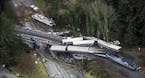 FILE- In this Dec. 18, 2017, file photo, cars from an Amtrak train that derailed lie spilled onto Interstate 5 in DuPont, Wash. Federal investigators 