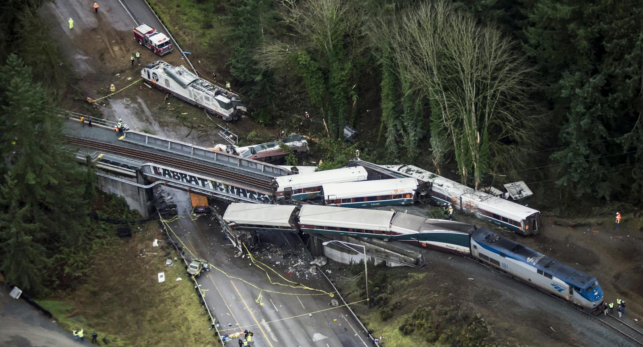 FILE- In this Dec. 18, 2017, file photo, cars from an Amtrak train that derailed lie spilled onto Interstate 5 in DuPont, Wash. Federal investigators say video aboard the Amtrak train that derailed in Washington state shows crews weren't using personal electronic devices and that the engineer remarked about the speed six seconds before the train went off the tracks south of Seattle. (Bettina Hansen /The Seattle Times via AP, File)