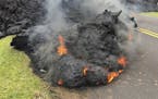 Lava from the Kilauea volcano moves across the road in the Leilani Estates in Pahoa, Hawaii, Saturday, May 5, 2018. Hundreds of anxious residents on t