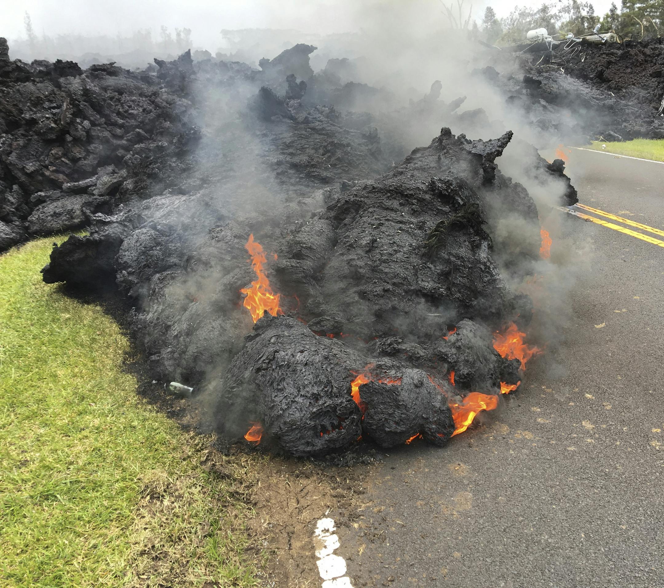 Lava from the Kilauea volcano moves across the road in the Leilani Estates in Pahoa, Hawaii, Saturday, May 5, 2018. Hundreds of anxious residents on the Big Island of Hawaii hunkered down Saturday for what could be weeks or months of upheaval as the dangers from an erupting Kilauea volcano continued to grow. (AP Photo/Marco Garcia)