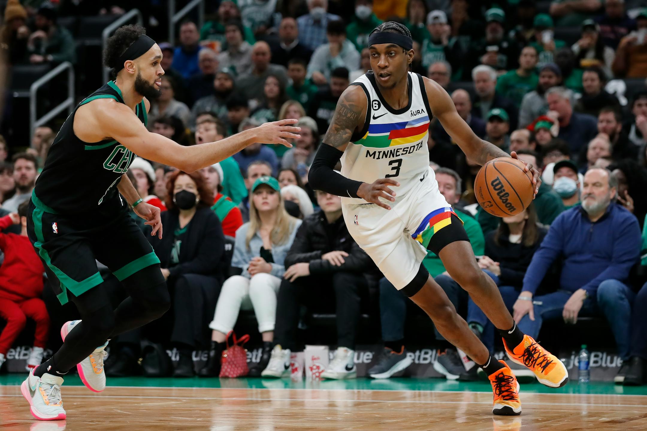 Minnesota Timberwolves' Jaden McDaniels (3) drives past Boston Celtics' Derrick White (9) during the first half of an NBA basketball game, Friday, Dec. 23, 2022, in Boston. (AP Photo/Michael Dwyer)