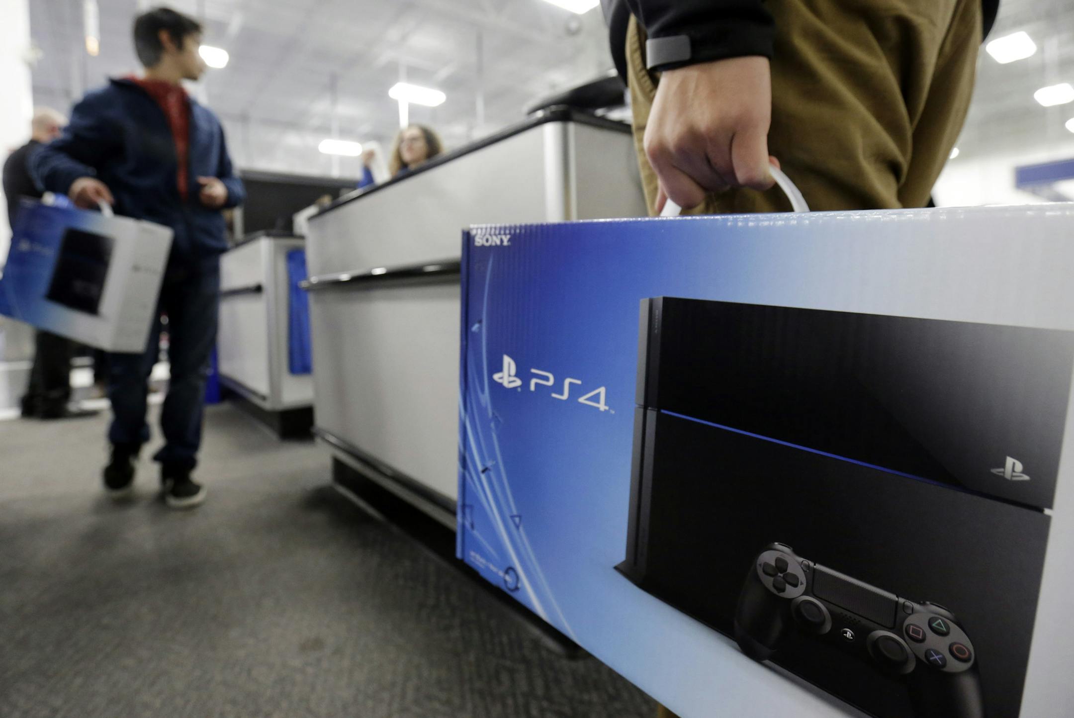 A man holds a Sony PlayStation 4 after he purchased it at the Lincoln Park Best Buy store in Chicago on Friday, Nov. 15, 2013. The PlayStation 4, which launched Friday, and the Xbox One, which goes on sale next week, face a much-changed gaming and entertainment landscape than their predecessors. (AP Photo/Nam Y. Huh)