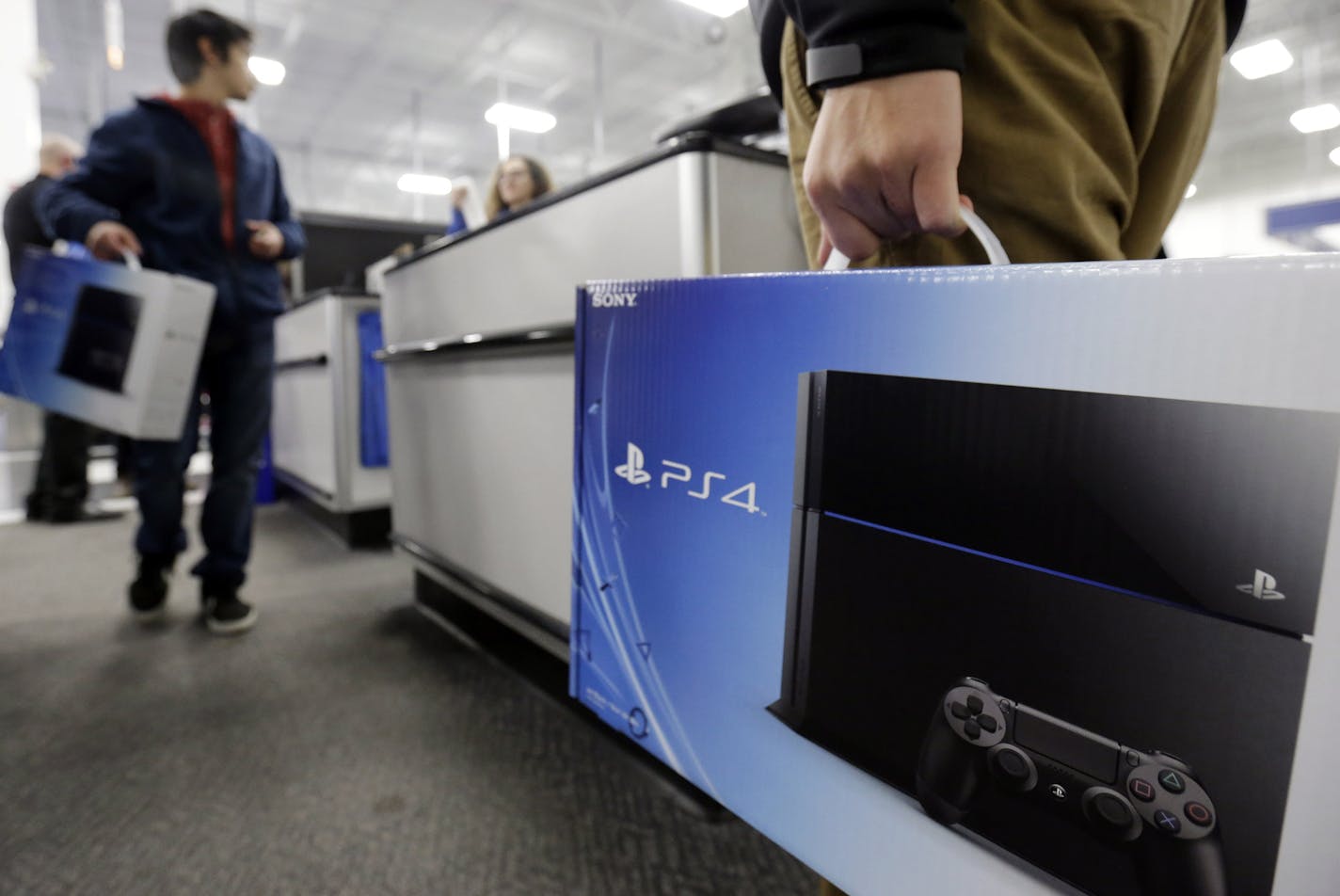 A man holds a Sony PlayStation 4 after he purchased it at the Lincoln Park Best Buy store in Chicago on Friday, Nov. 15, 2013. The PlayStation 4, which launched Friday, and the Xbox One, which goes on sale next week, face a much-changed gaming and entertainment landscape than their predecessors. (AP Photo/Nam Y. Huh)