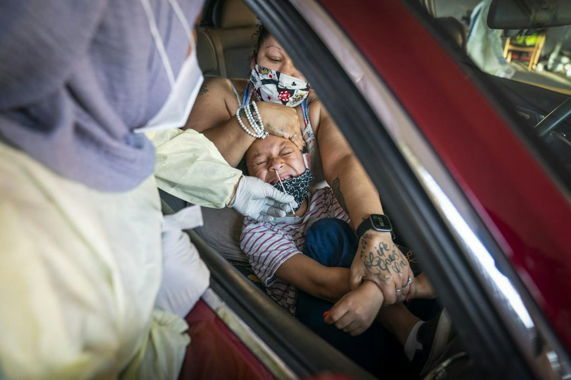 Jessica Steele of St. Paul held her son Little Bear Chatman, Jr., 6, as he was tested at the drive-through COVID-19 testing site at North Memorial Health in Robbinsdale.