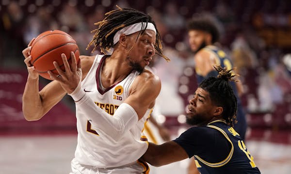 Minnesota forward Brandon Johnson (23) grabbed a rebound as Michigan guard Mike Smith (12) defended in the first half.