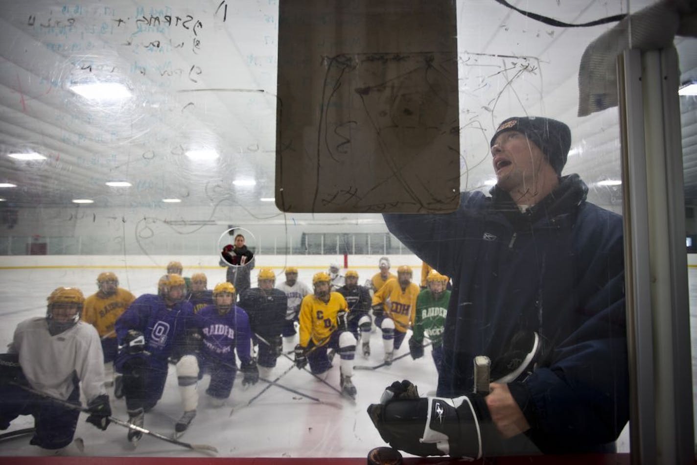 With Krissy framed by the hole in the glass, Johnny Pohl went through plays with his Cretin-Derham Hall girls' hockey players.