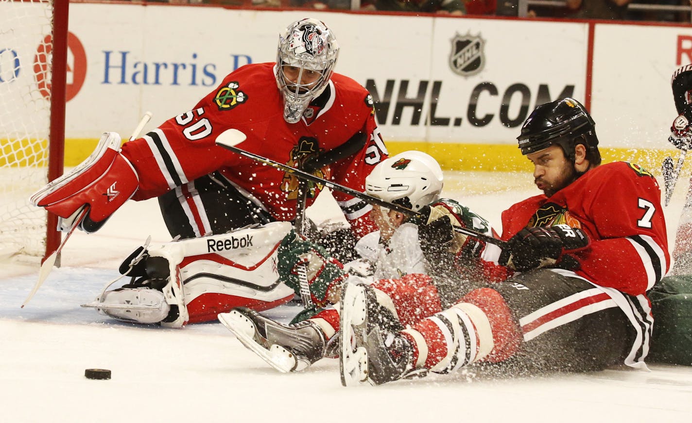 Wild center Cody McCormick (8) and Chicago defenseman Brent Seabrook (7) slide into Chicago goalie Corey Crawford (50) during the third period Sunday.