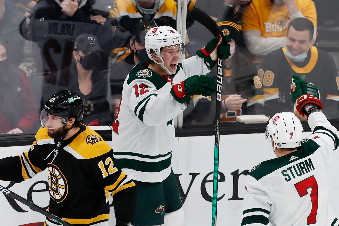 Minnesota Wild's Matt Boldy, center, celebrates his goal with Nico Sturm (7) as Boston Bruins' Craig Smith skates away during the second period of an NHL hockey game Thursday, Jan. 6, 2022, in Boston. (AP Photo/Michael Dwyer)