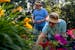 Janice, left, and Janet Robidoux trim flowers and pull weeds from their garden in Coon Rapids. The 86-year old twin sisters have been maintaining thei