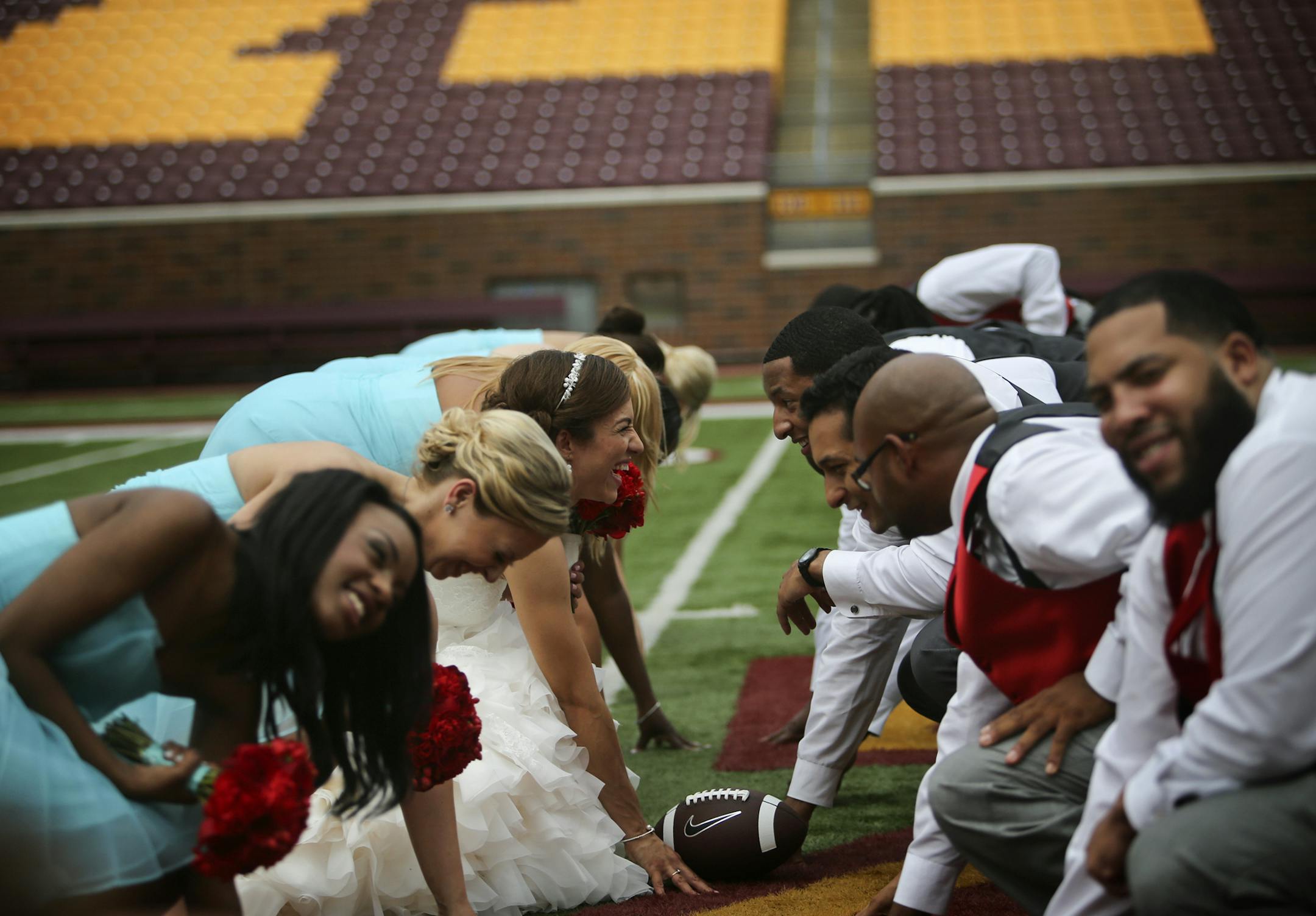 Bride Samantha Dean and groom Desmond Jones line up on the football field with their attendants.