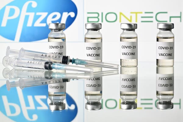 An illustration picture shows vials with Covid-19 Vaccine stickers attached and syringes with the logo of US pharmaceutical company Pfizer and German 