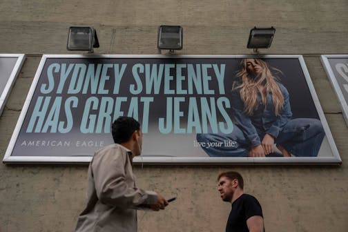 People walk past a campaign poster starring Sydney Sweeney which is displayed at the American Eagle Outfitters store on Aug. 1 in New York.