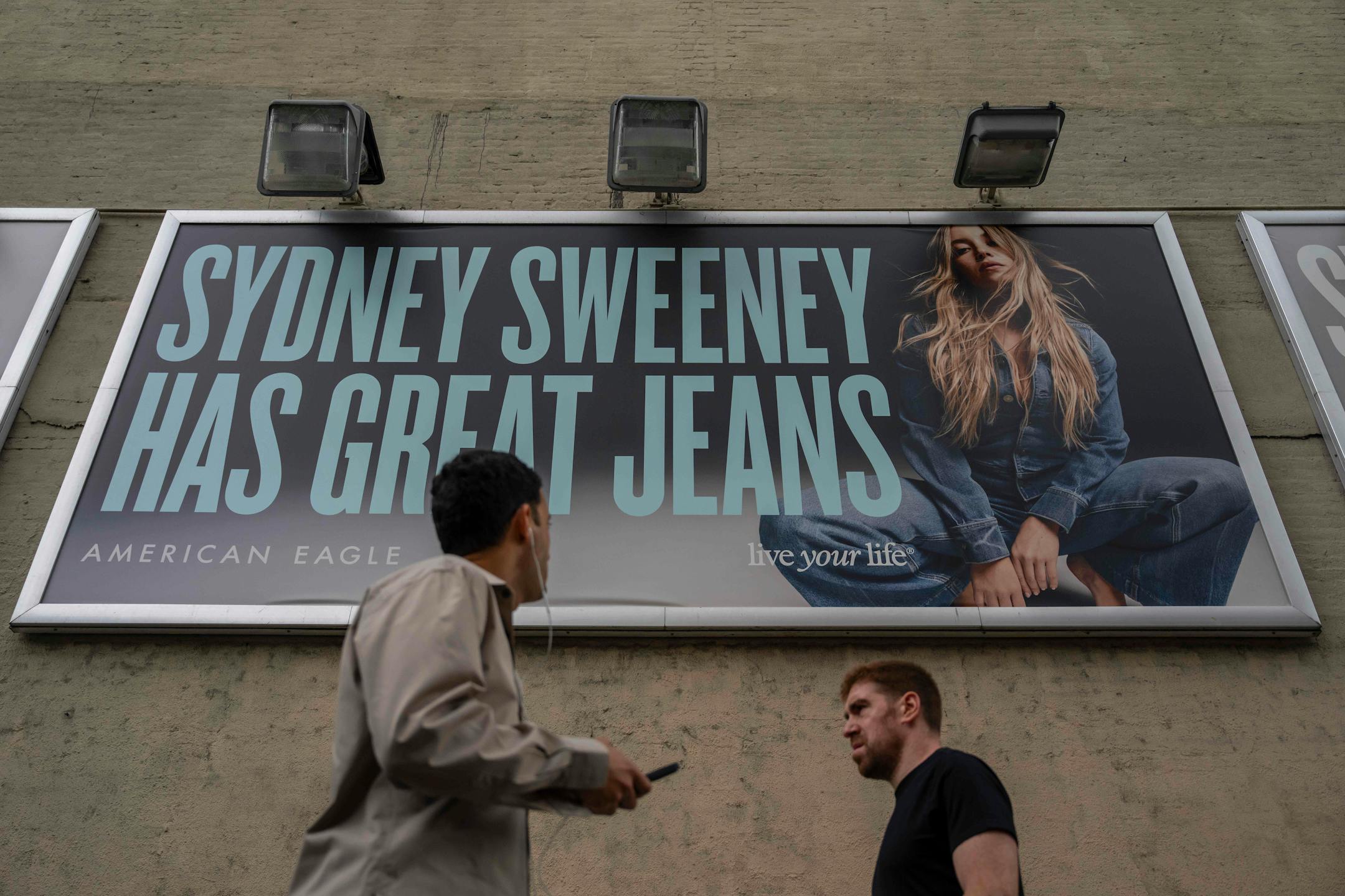 People walk past a campaign poster starring Sydney Sweeney which is displayed at the American Eagle Outfitters store on Aug. 1 in New York.
