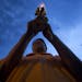 A Thai Buddhist carrying a candle and lotus prays in front of Marble Temple in Bangkok Tuesday, May 13, 2014 as part of Wesaka Bucha activities. Wesak