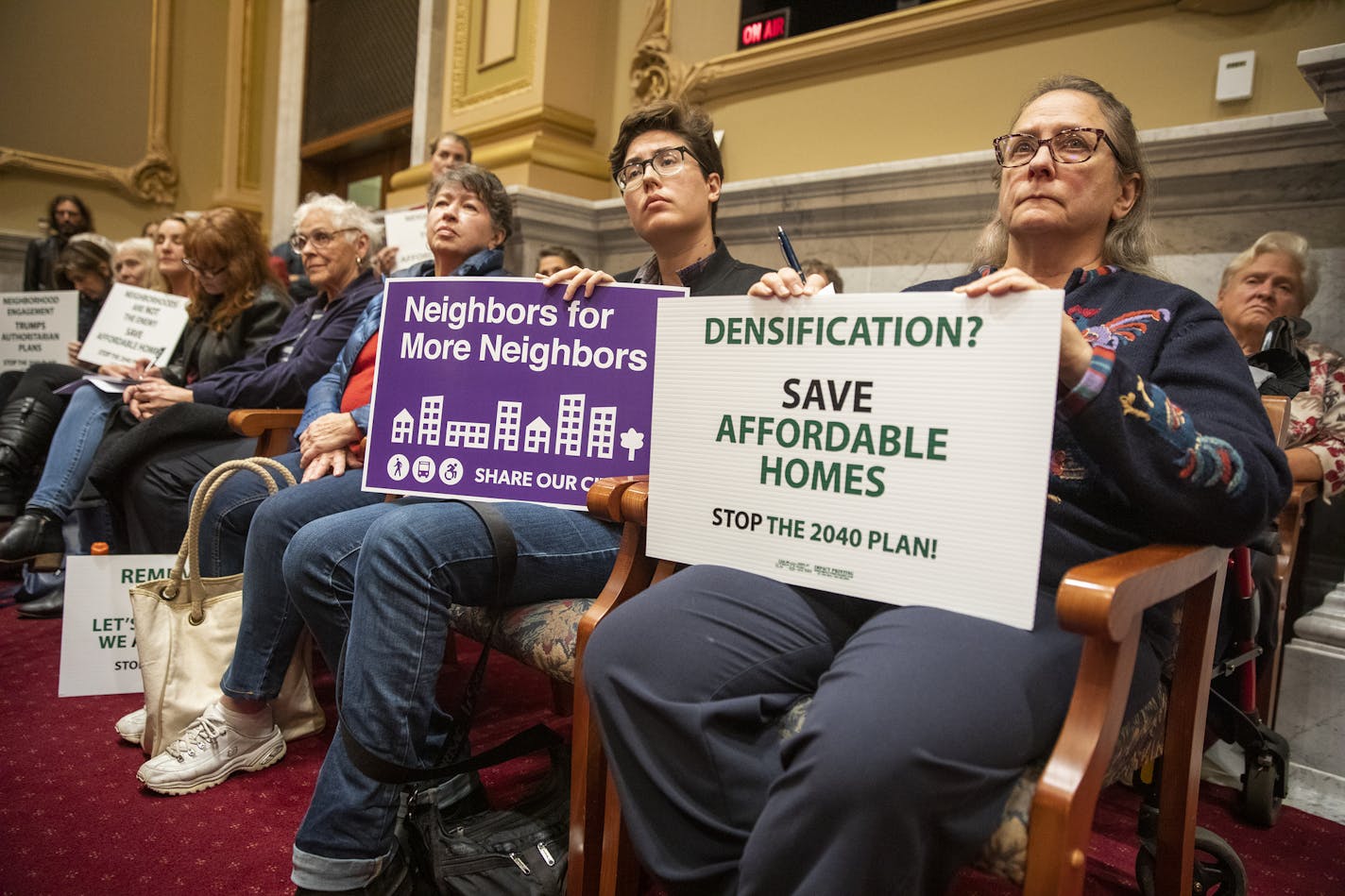 Nancy Przymus, from right, holds a sign against the 2040 Comprehensive Plan, as her neighbor Blue Delliquanti holds a sign supporting the plan during a meeting last October.