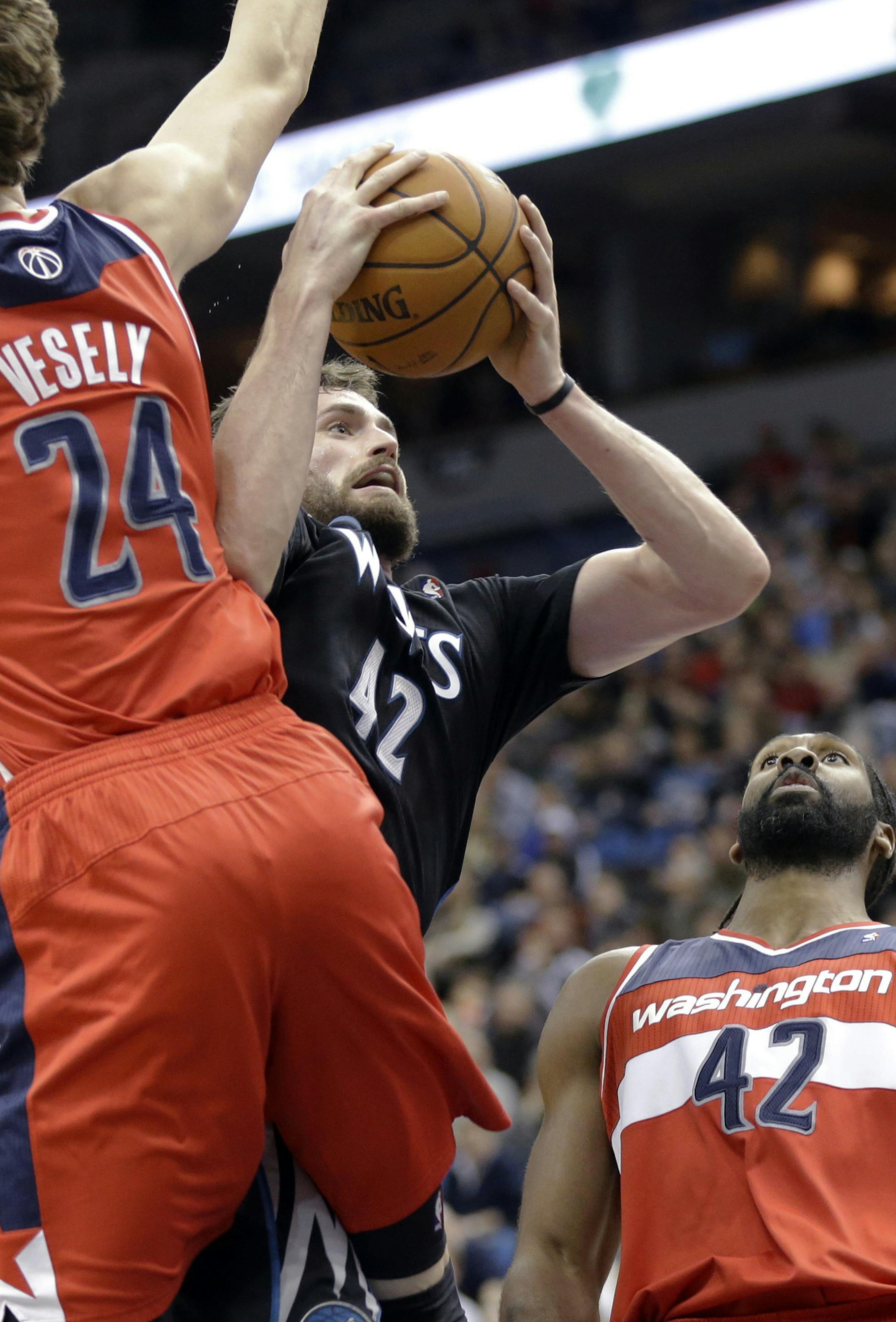 Minnesota Timberwolves' Kevin Love lays up a shot between Washington Wizards' Jan Vesely, left, of the Czech Republic, and Nene Hilario, of Brazil, during the first quarter of an NBA basketball game, Friday, Dec. 27, 2013, in Minneapolis. (AP Photo/Jim Mone)