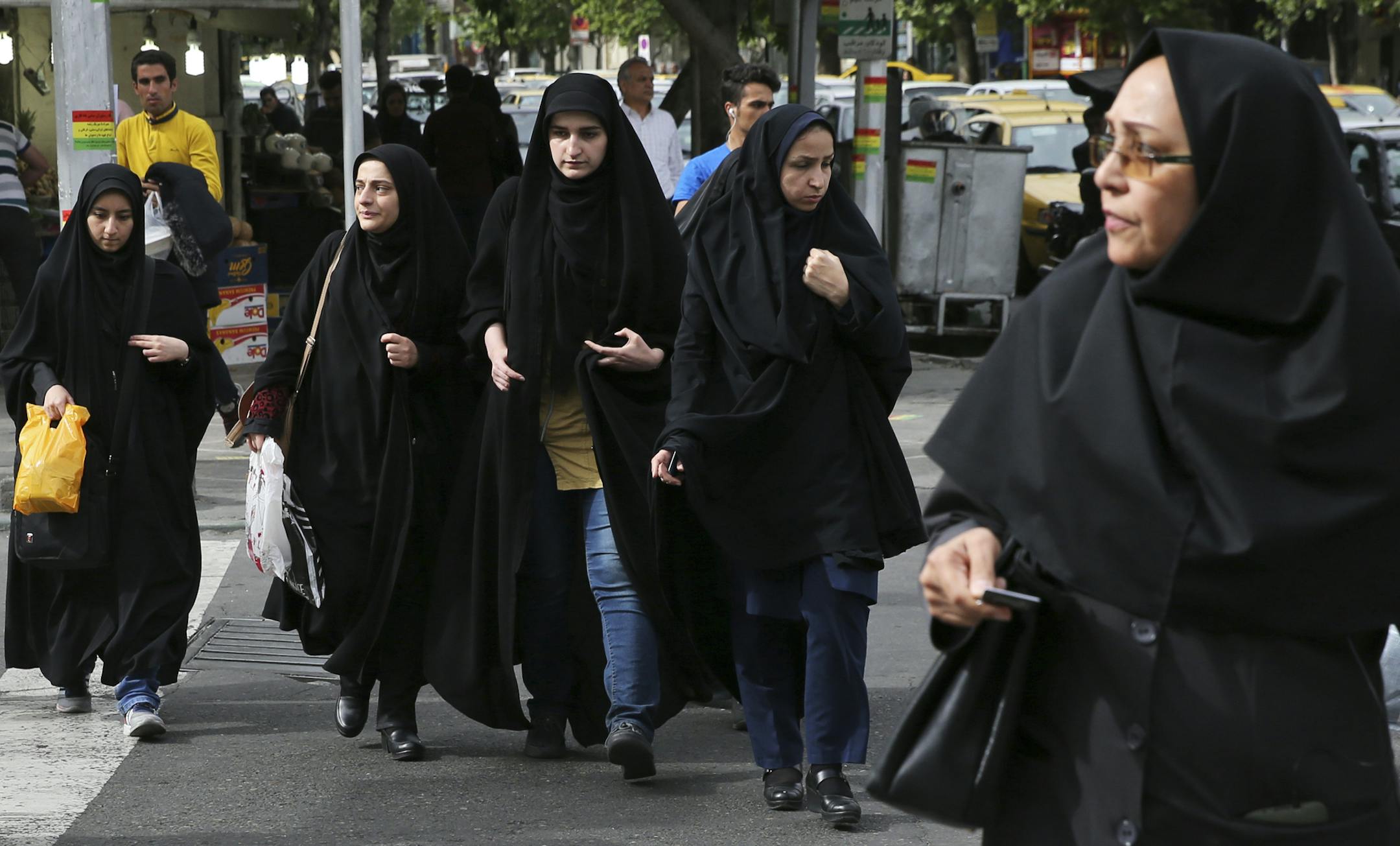 In this Sunday, April 22, 2018, photo, head-to-toe veiled Iranian women cross a street in Tehran, Iran. A grainy video of female officers from Iran&#x2019;s morality police assaulting a young woman whose headscarf only loosely covered her hair has sparked a new public debate on the decades-long requirement for women in the Islamic Republic. (AP Photo/Vahid Salemi)