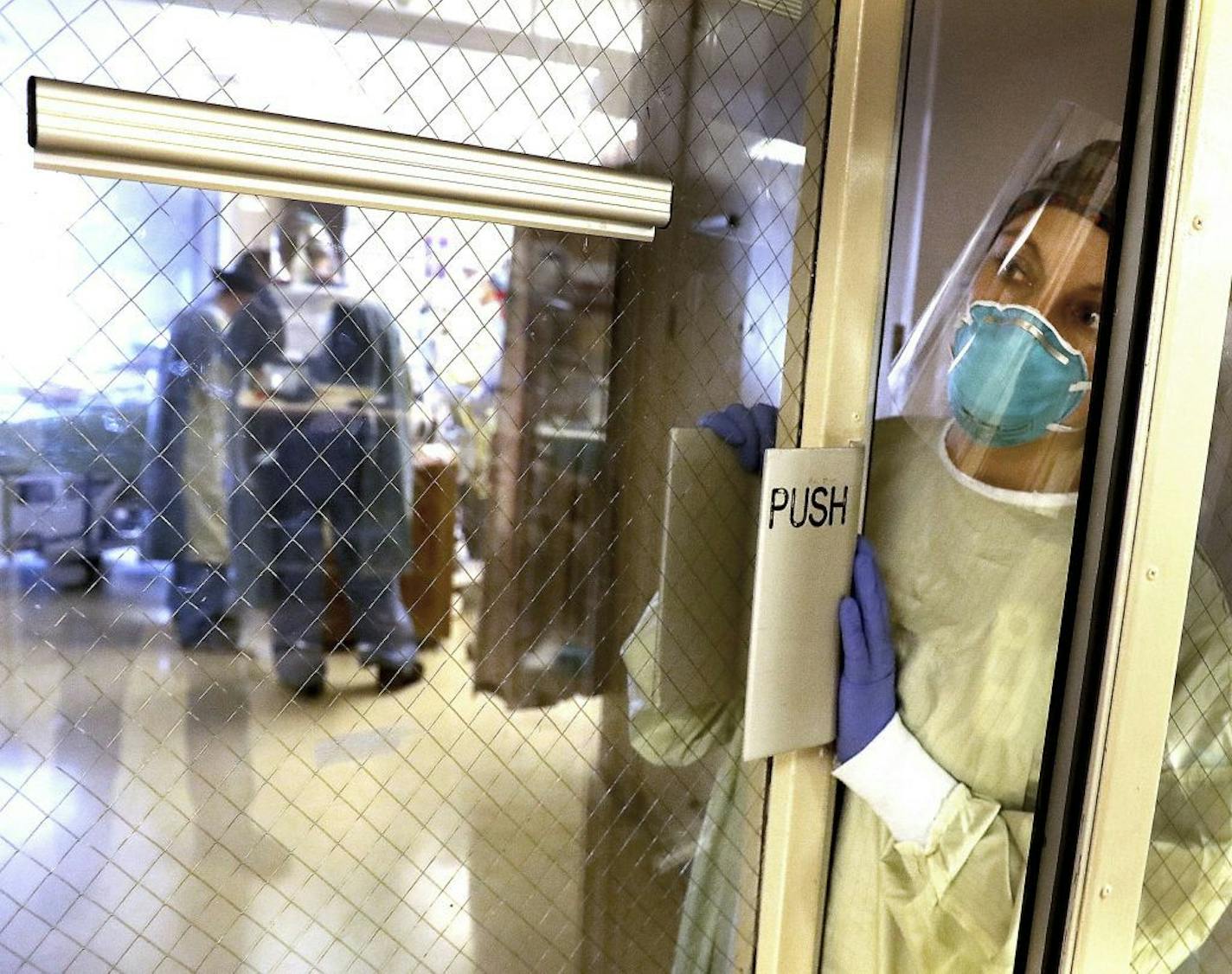 Leah Chapman, a registered nurse, waits for a protective gown before the healthcare team rotated a COVID-19 patient on the third-floor ICU at Bethesda Hospital on Thursday, May 7, 2020, in St. Paul, Minn. Every time a COVID-19 patient leaves Bethesda Hospital alive, a bell rings throughout the St. Paul facility. Its a moral-booster for doctors and nurses.