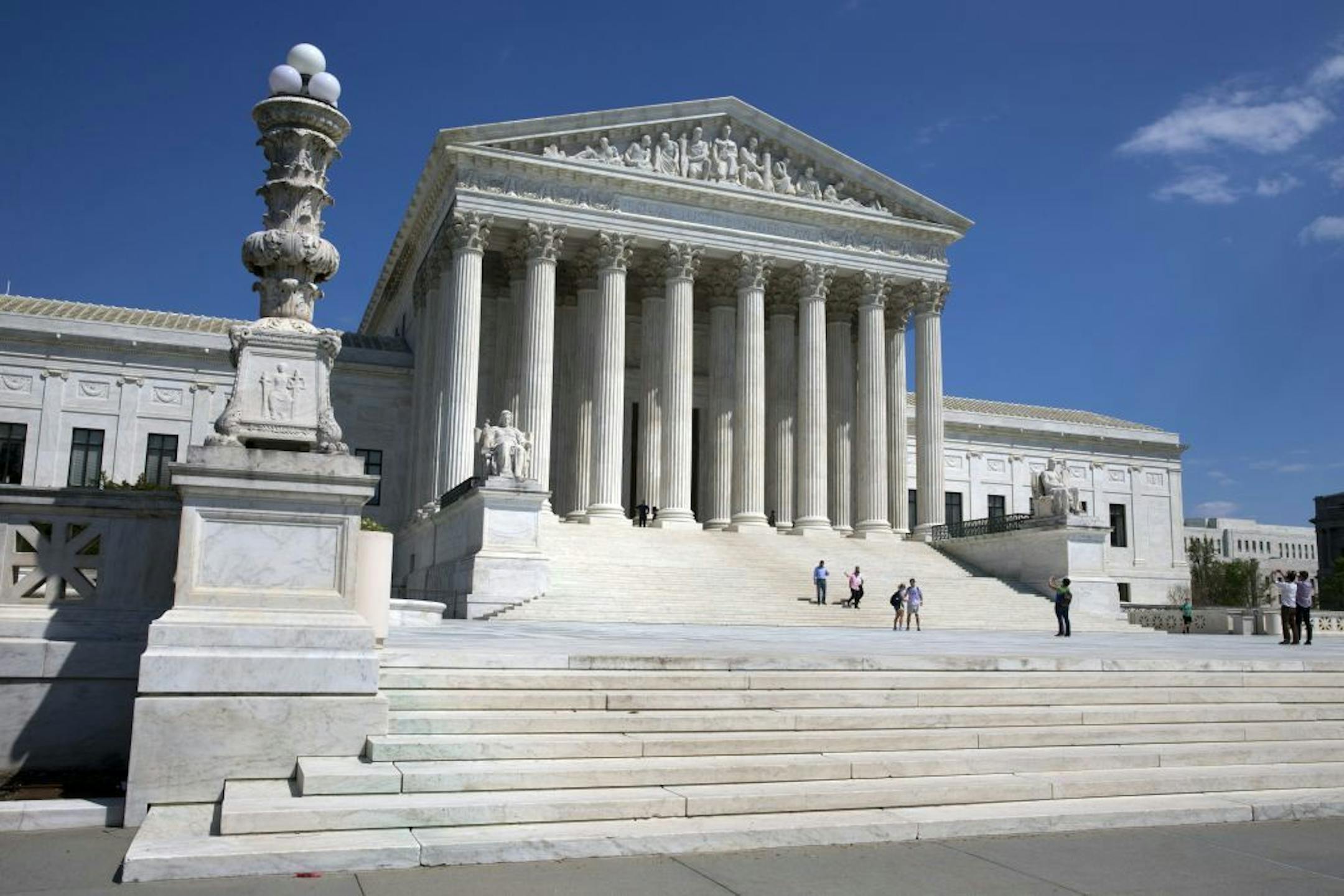 FILE - In this April 26, 2014 file photo, people walk on the steps of the U.S. Supreme Court in Washington. The Supreme Court said Monday that prayers that open town council meetings do not violate the Constitution even if they routinely stress Christianity.