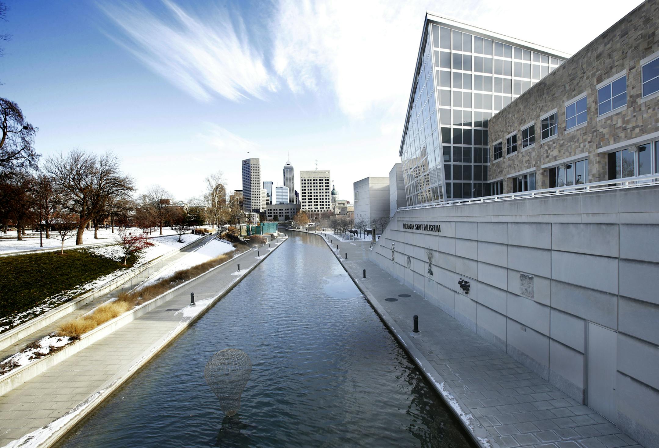 The Indiana State Museum sits along the Indiana Central Canal, with the skyline of downtown Indianapolis in the distance, Dec. 13, 2013. Cyclists and pedestrians in Indianapolis have a new eight-mile landscaped path connecting all of the downtown's major arts venues, a resource that is already helping both tourists and locals discover the city's cultural heritage. (AJ Mast/The New York Times) -- PHOTO MOVED IN ADVANCE AND NOT FOR USE - ONLINE OR IN PRINT - BEFORE MARCH 09, 2014.