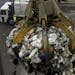 A crane grapple lifts a load of garbage for mixing before it is brought into the boiler for waste to energy conversion as a garbage truck dumps its lo