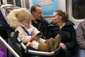 A baby girl played with a mobile device while riding a New York subway.