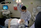 Andrew Bosworth, dental student, prepared to take a look at the teeth of Norma Inemela, New Hope, 87. ] (KYNDELL HARKNESS/STAR TRIBUNE) kyndell.harkne