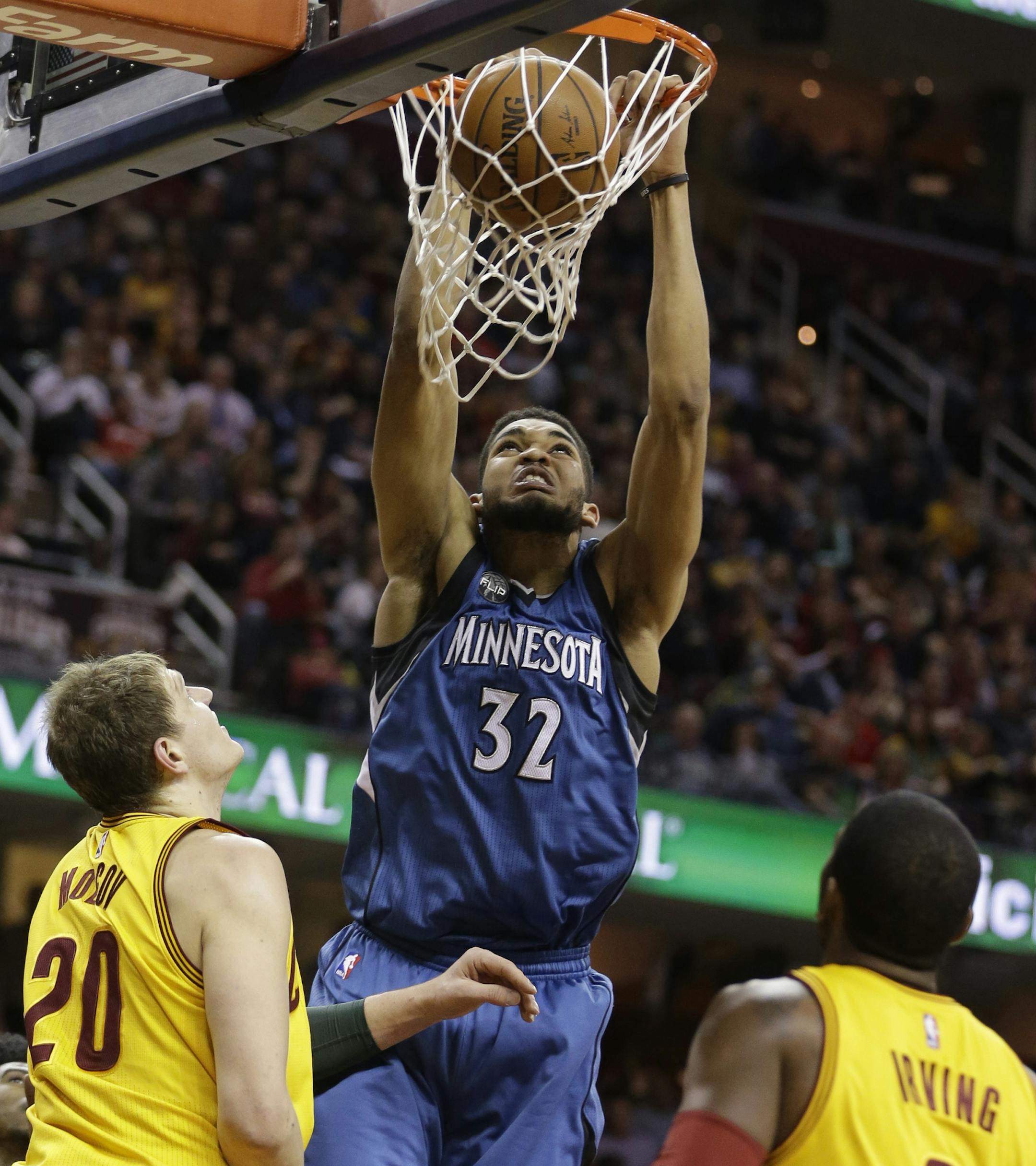 Minnesota Timberwolves' Karl-Anthony Towns (32) dunks the ball against Cleveland Cavaliers' Timofey Mozgov (20), from Russia, and Kyrie Irving (2) in the second half of an NBA basketball game Monday, Jan. 25, 2016, in Cleveland. The Cavaliers won 114-107. (AP Photo/Tony Dejak)