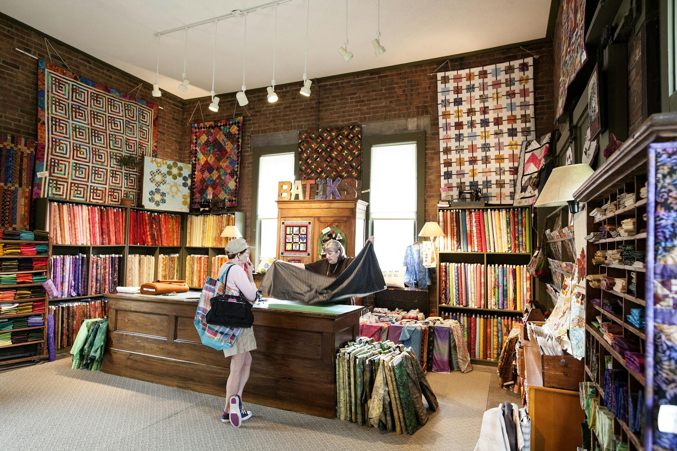 Employee Kim Simenson, right, helps a customer in the freight room of the restored railroad depot that houses Eagle Creek Quilt Shop in Shakopee August 23, 2014. (Courtney Perry/Special to the Star Tribune)