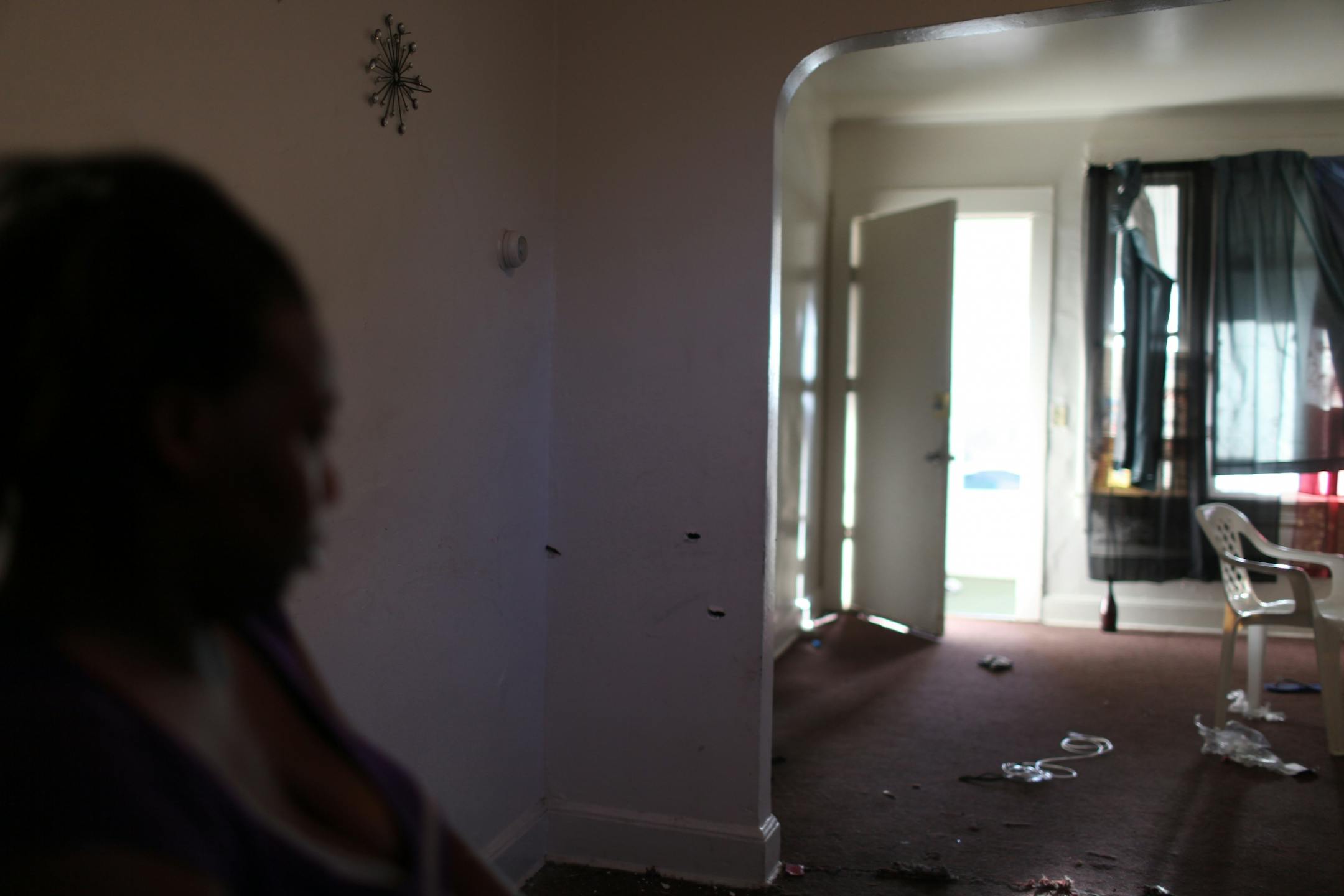 Emma Mercer sits in the downstairs of the home at 1527 Queen Ave. North Thursday morning next to a wall with three bullet holes. Wednesday evening someone fired as many as 11 shots into the home throught a first floor window, wounding two men, a woman and a child who were taken to nearby North Memorial Medical Center and were expected to survive.