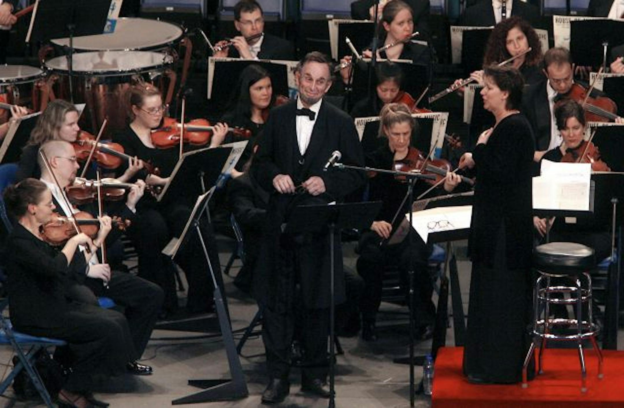 Billed as a musical extravaganza, "Let Freedom Sing!" took place Wednesday evening at the Prairie Capital Convention Center. Abraham Lincoln, played by Fritz Klein, is serenaded to the song Happy Birthday-played by the Illinois Symphony Orchestra, under the direction of Karen Lynne Deal, right, Wednesday, Feb. 11, 2009 in Springfield, Ill.. More than 500 church and student singers from the area took part in singing patriotic and inspirational music.