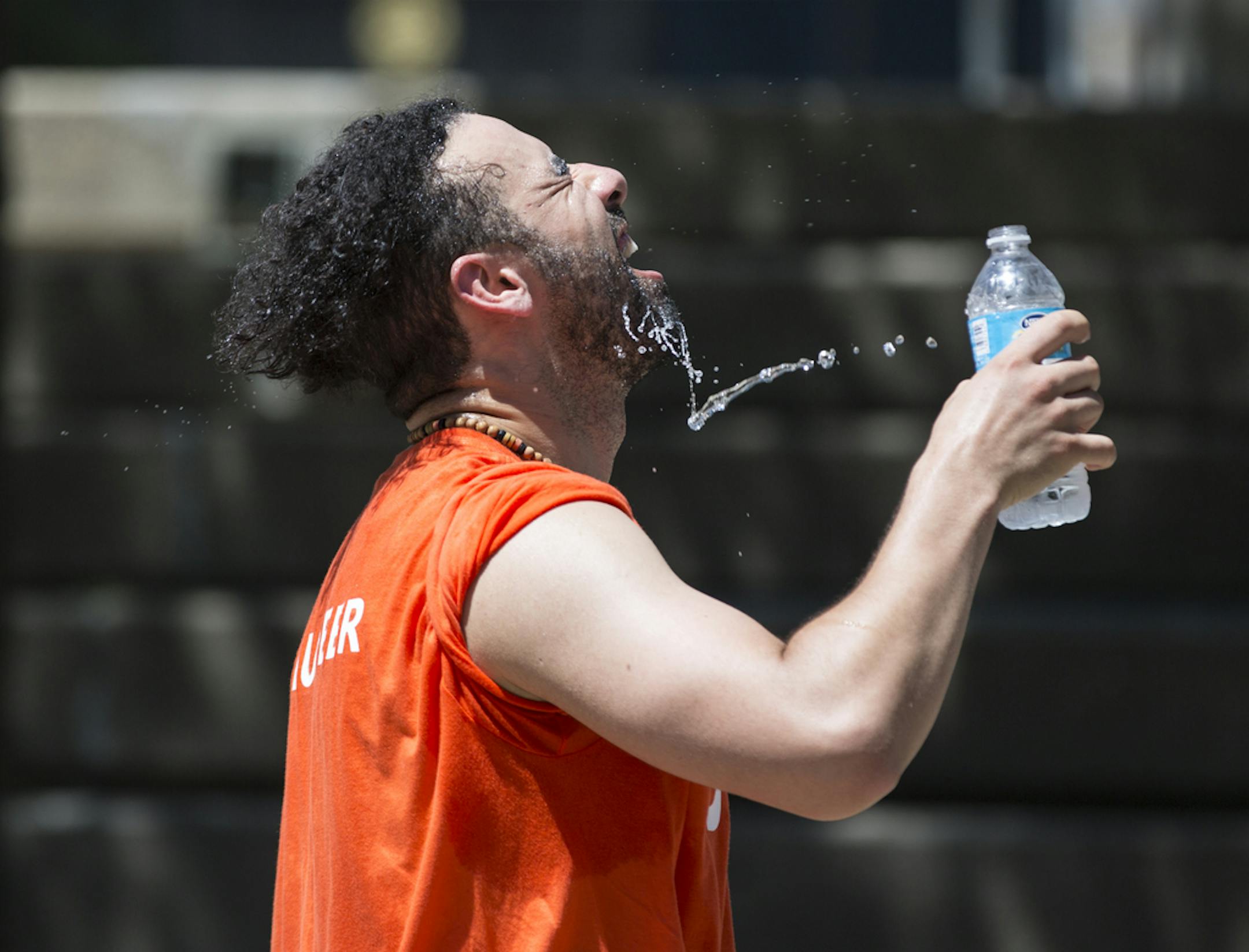 A sweaty Mehdi Kennar poured water on his face during a water break from his world dance workout during the Aquatennial Zumba presented by YWCA in the 90-degree weather at Peavy Park in Minneapolis, Minn., on Friday, July 22, 2016. ] RENEE JONES SCHNEIDER ¥ reneejones@startribune.com