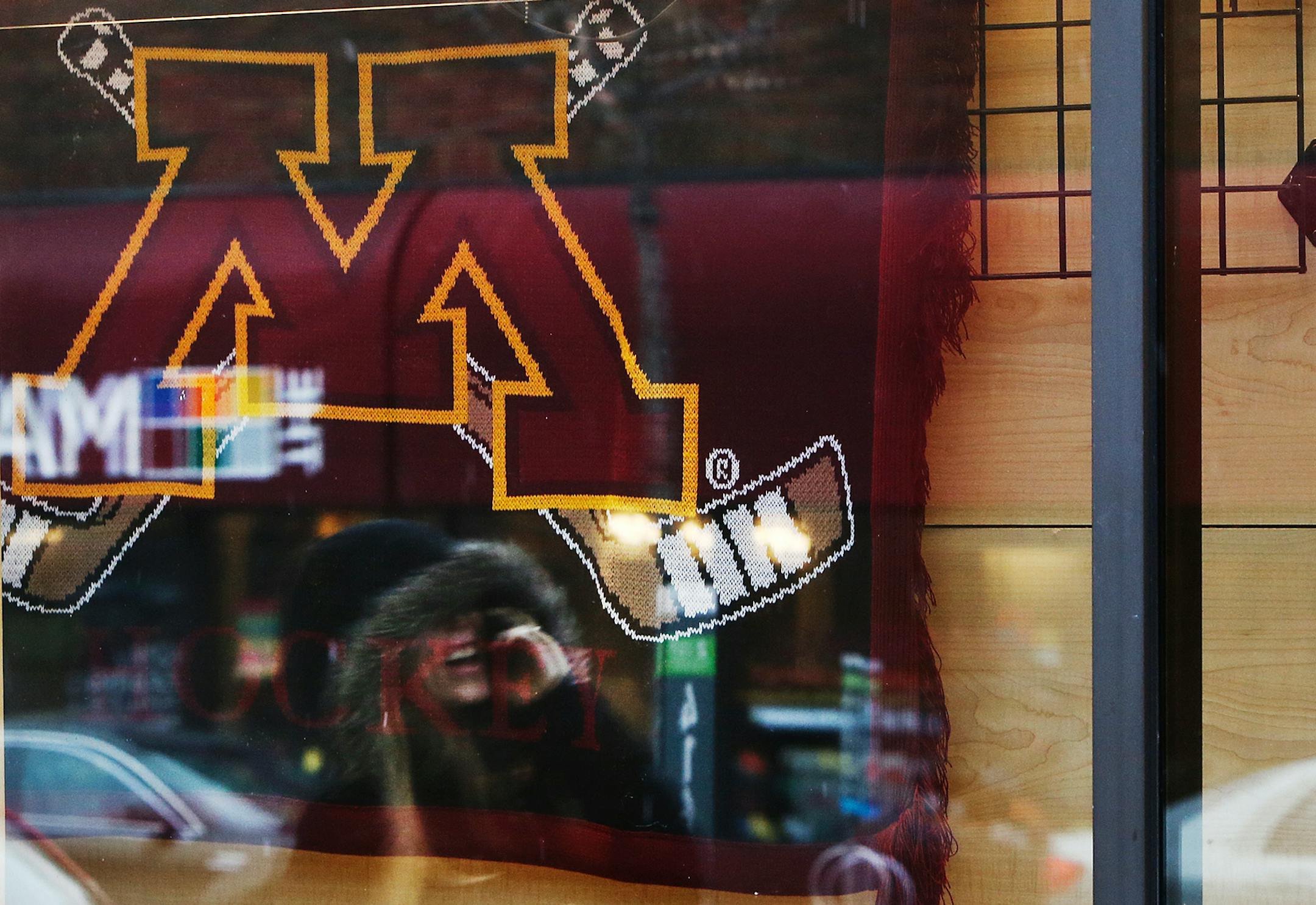In this file photo, a student is reflected in a window walking past the store front of Gold Country in Dinkytown near the University of Minnesota campus.