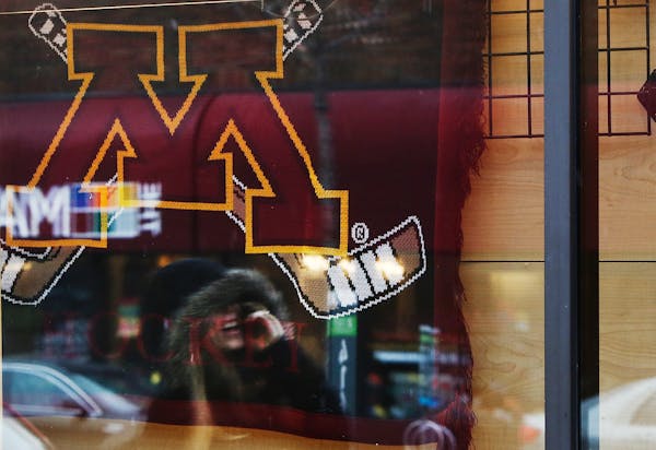 In this file photo, a student is reflected in a window walking past the store front of Gold Country in Dinkytown near the University of Minnesota camp