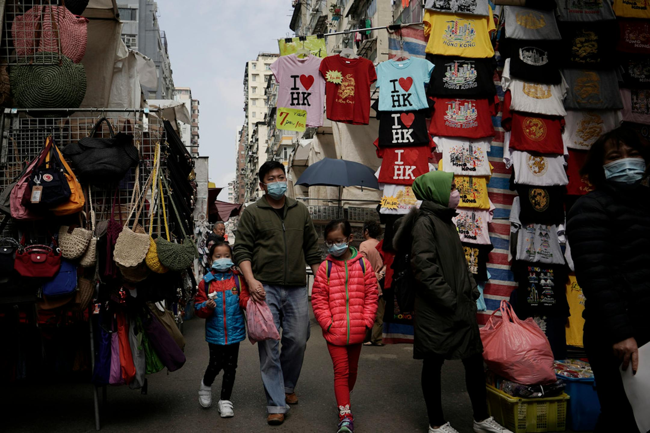People wear masks at a street where is selling tourist's souvenir in Hong Kong, Saturday, Feb, 1, 2020.