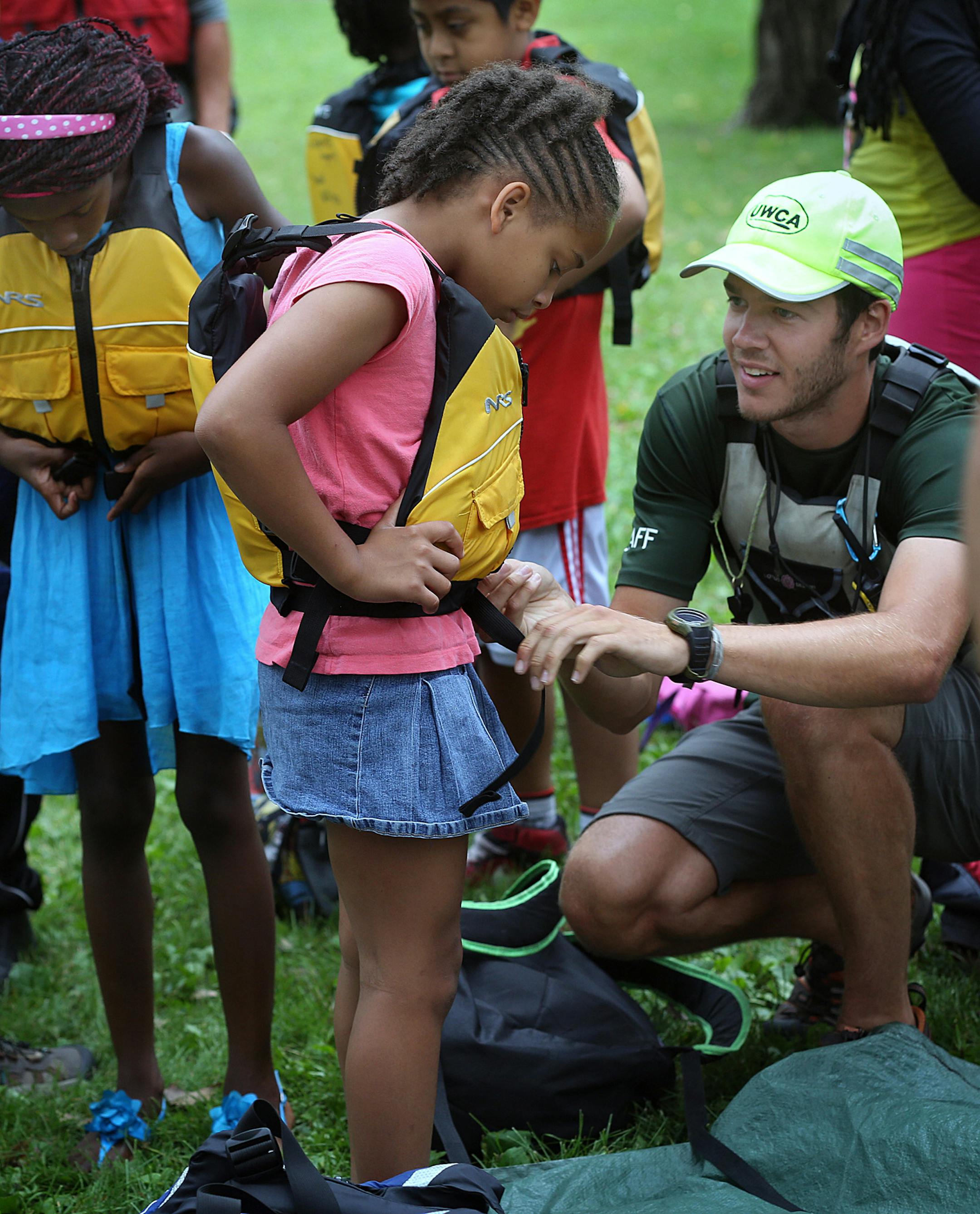 Trail staff member Brandon Liddiard helped Angelica, 10, to secure a life jacket before the trip down the Mississippi River. ] JIM GEHRZ &#xef; james.gehrz@startribune.com / St. Paul, MN / August 7, 2015 / 11:00 AM &#xf1; BACKGROUND INFORMATION: Wilderness Inquiry is leading a paddle for YMCA children, starting at Hidden Falls Regional Park. Photos of children on canoe outing.