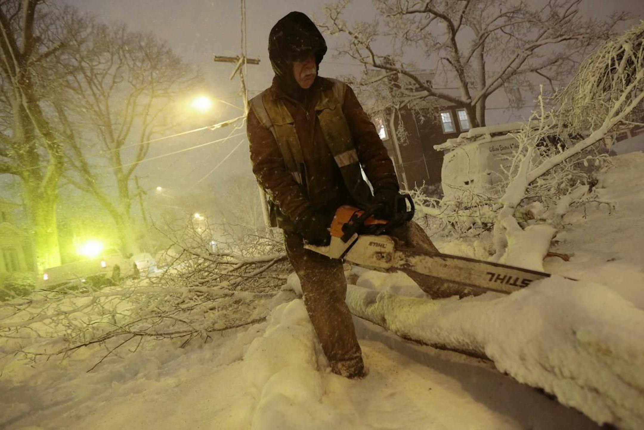 Louie Rodriguez of the New Bedford Forestry Department cuts a fallen tree at the intersection of Rotch St. and Maple St. in New Bedford, Mass., on Friday, Feb. 8, 2013, after heavy snow and winds from a storm.