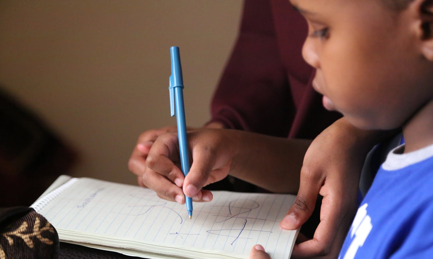 Suhayb Ali, 5, with his sister, Hamdi Sheikhsaid, 20, wrote his name. ] (KYNDELL HARKNESS/STAR TRIBUNE) kyndell.harkness@startribune.com Suhayb Ali and his family in St Paul, Min., Friday, July 10, 2015.